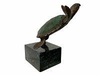 Side view of bronze turtle sculpture with green patina on shell and mounted on square marble base.