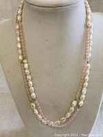 Front and center view of the necklace displayed on a white bust mannequin showing the arrangement of pearls and rose quartz beads.