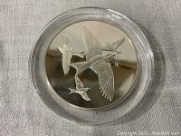Front side of the silver proof medal showing embossed Purple Martin birds in flight within a clear plastic case.