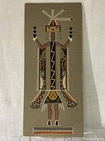 Front view of the large Mountain-God Navajo sand painting featuring detailed figure and natural earth tones on a rectangular board.