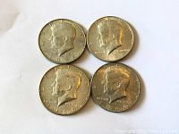 Obverse side showing the four Kennedy half dollars dated 1966 (three coins) and 1968 (one coin) with John F. Kennedy profile.