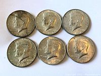 Obverse view of six 1967 Kennedy half dollars showing John F. Kennedy portrait with date and 'In God We Trust' inscription.