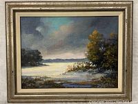 Full view of the framed oil painting showing a water scene with light reflection, trees, and a cloudy sky.