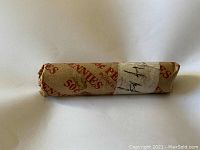Photo of a roll of 1944 wheat pennies wrapped in original brown paper with printed text for 50 pennies and a white label marked '44'.