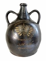 Full view of the vintage Austrian tin glazed wine jug showing the oblong rounded body with two handles, dark glaze, and gold grape cluster decoration with text