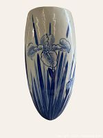 Front view of vintage ceramic wall pocket vase with blue iris floral design on white background.