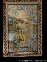 Front view of the Asian decorative picture featuring painted figures in a rectangular panel with a blue and white patterned border, enclosed in a wooden frame with visible damage.