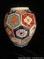 Side view of the hexagonal porcelain vase showing various floral patterns in red, blue, white, and teal.