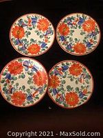 Top view showing the colorful floral design with orange flowers and green leaves on four plates.