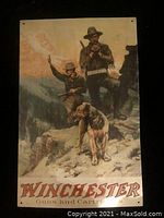 Front of vintage metal Winchester advertising sign showing two hunters and dog with 'Winchester Guns and Cartridges' text