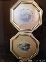 Two octagonal gold-tone framed miniature portraits stacked vertically, showing both artworks with reflective glass.