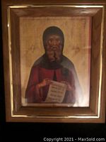 Frontal view of vintage religious picture in wooden frame showing saint figure holding scroll.