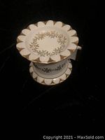 Front view showing scalloped edge with gold leaf pattern decoration on top of white ceramic tape dispenser