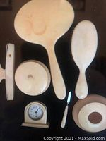 Photo shows vintage ivory vanity set items including a large hand mirror with stains, small brush, clock without back, small round lid, and a nail/cuticle tool.