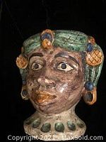 Front view of the ceramic pot showing the detailed sculpted woman's face with painted features, earrings, and a green-blue headwrap.