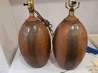 Two pottery lamp bases shown side by side with brass lamp hardware attached