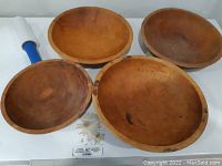 Four vintage wooden bowls arranged on a white surface showing size and condition.