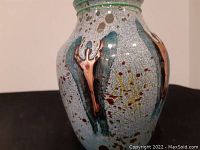 Side view of vase showing aqua speckled glaze and copper appliqués