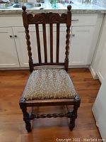 Full view of chair showing barley twist front legs and back supports, carved top rail, and upholstered seat.