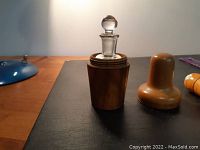 Full exterior view of the wooden perfume bottle case with lid beside the glass stopper bottle.