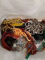 Close-up photo showing multiple beaded necklaces in various colors packed together in a container.