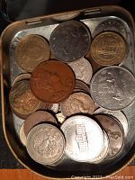Close view of coins in metal container showing various designs