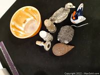 Overview of bowl, bird figurines, and bottle stoppers on black surface with ruler