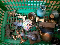 Full overview of the miniature lot showing items in a green basket, including brass, ceramic, metal figurines and mini vases, and a colorful glass paperweight.