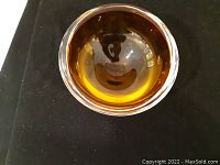 Top-down view of the amber glass bowl showing round opening and smooth edges on black background.