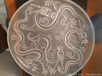 Top-down view of round frosted glass bowl featuring four sinuous dragons in relief radiating from center