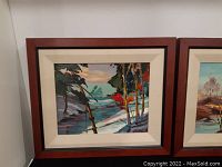 Framed signed oil painting depicting a riverside landscape with colorful trees and distant mountains under blue sky.
