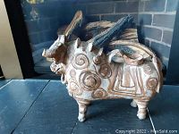 Side view of handcrafted Torito de Pucara bull showing painted traditional patterns and terra cotta surface, with some wear.