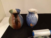 Both pottery vases side by side on a black surface to show size and appearance.