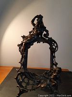 Front angled view showing full frame with reclining maiden and cherub at base