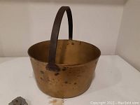 Full view of the Victorian brass jelly kettle showing round wide body and attached broad handle.