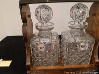 Front close-up of whisky and sherry decanters showing lattice cut pattern, clear faceted stoppers, and metal hang tags.