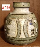 Front view of the pottery vase showing textured surface and raised geometric design in green and beige glaze.