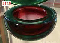 Side view of the Murano glass bowl showing green outer layer and deep red inner glass with smooth rounded sides.