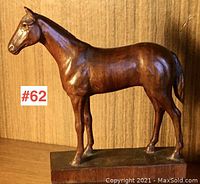 Front side view of the wooden horse carving showing detailed carving and warm brown finish with the base clearly visible.