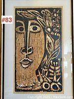Full view of the framed woodcut print depicting a stylized female face with floral elements on right side, black on tan background, signed and numbered.
