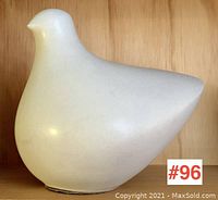 Front view of stylized white bird sculpture on wooden shelf