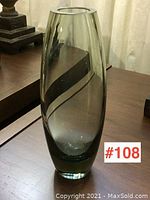 Front angle of vase placed on wooden surface showing green translucent glass with spiral swirl design.