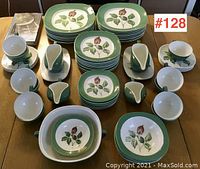 Overview of entire set including stacks of plates, bowls, cups, saucers, serveware, and book