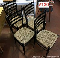 Group view of all four black wood chairs with woven rush seats gathered in a cluster
