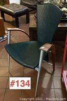 Front angled view of the green leather chair with wooden armrests and metal legs.