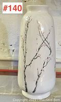 Full side view of the white ceramic vase showing hand-painted branches design.