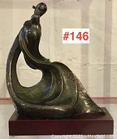 Front view of bronze sculpture showing abstract curved figure on wooden base with lot number