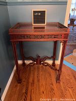 Full frontal view of carved wooden butler's table showing gallery top rails and fretwork apron.