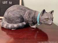 Side view of the vintage charcoal grey resting cat sculpture showing detailed fur texture, blue collar, and yellow eyes.