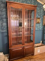 Front view closed: two glass-paneled upper doors, two wood lower doors, finish and hardware visible.